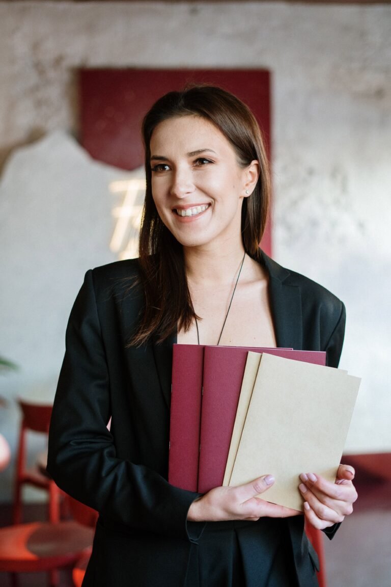 Young woman holding menus, smiling in stylish café interior.